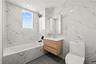 Full bath featuring vanity, tile walls, a combined bath / shower with marble appearance, and recessed lighting