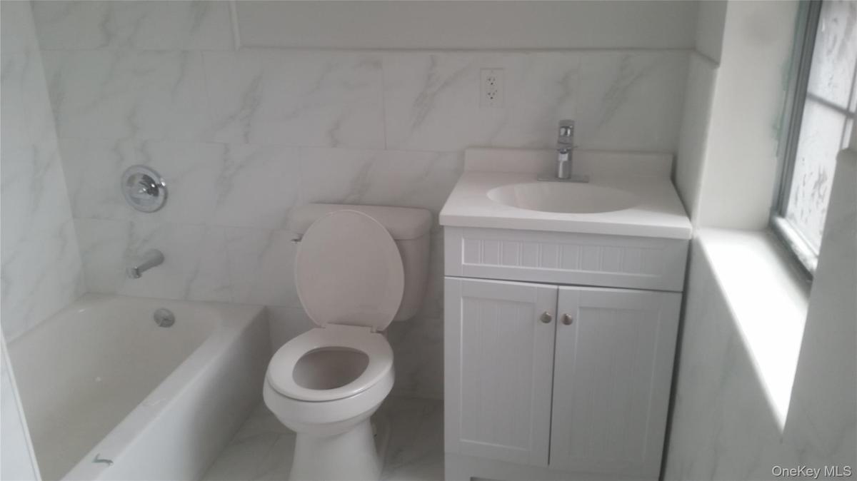 Bathroom with vanity, tile walls, and washtub / shower combination