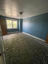 Empty room featuring a baseboard heating unit and dark colored carpet