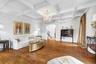 Hardwood flooring and a coffered ceiling with a crystal chandelier illuminate the living space, featuring an arched doorway and a built-in display cab