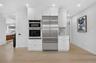 Integrated stainless steel appliances, white cabinetry with crown molding, light wood-finish flooring, and recessed lighting