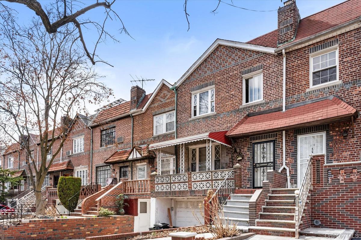 Multi unit property with brick siding, a chimney, and a garage