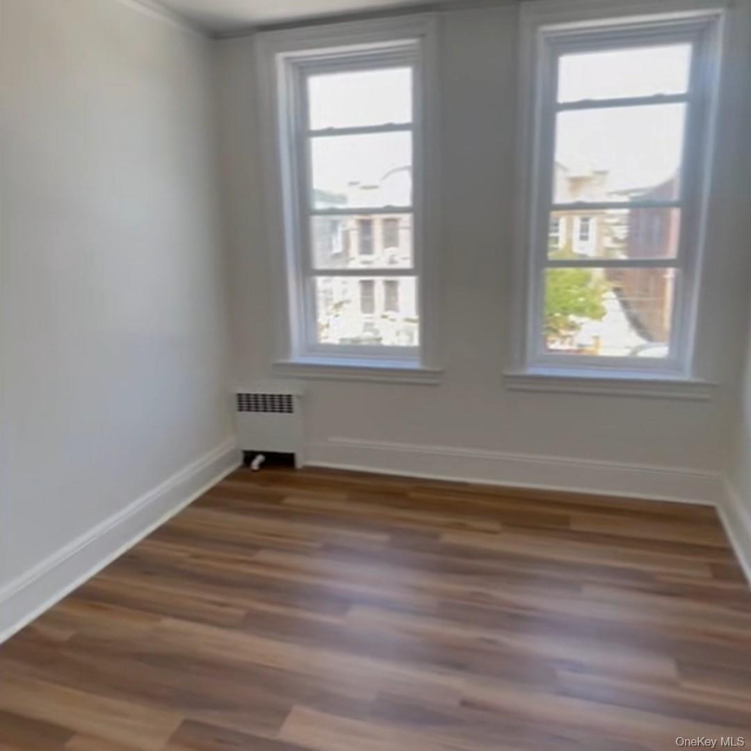 Unfurnished room with dark wood-type flooring and radiator heating unit
