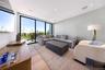 Living room with light wood-style flooring, floor to ceiling windows, and recessed lighting
