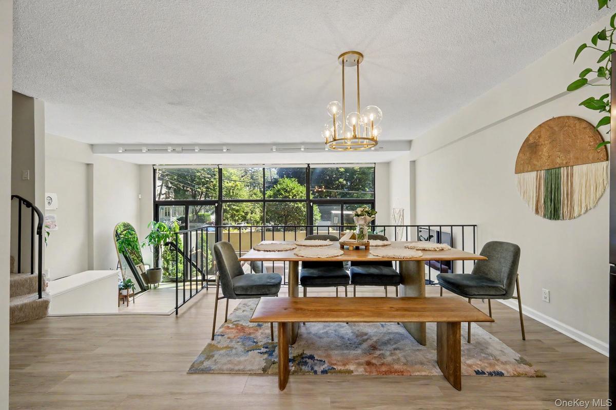 The sun-filled, two-story living room is a dramatic centerpiece of the home, featuring a soaring wall of glass and two sets of glass doors opening dir