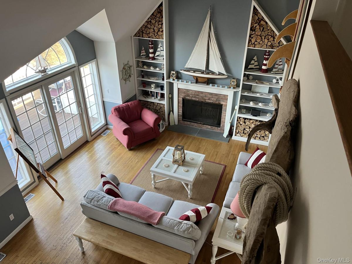 Living room featuring a fireplace, light wood-style floors, high vaulted ceiling, and built in features