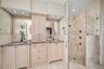 Primary bathroom with dual vanities and glass enclosed shower
