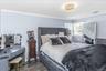 Spacious room featuring light blue walls, crown molding, a decorative flush-mount ceiling fixture, two windows with blinds, and wood-finish flooring