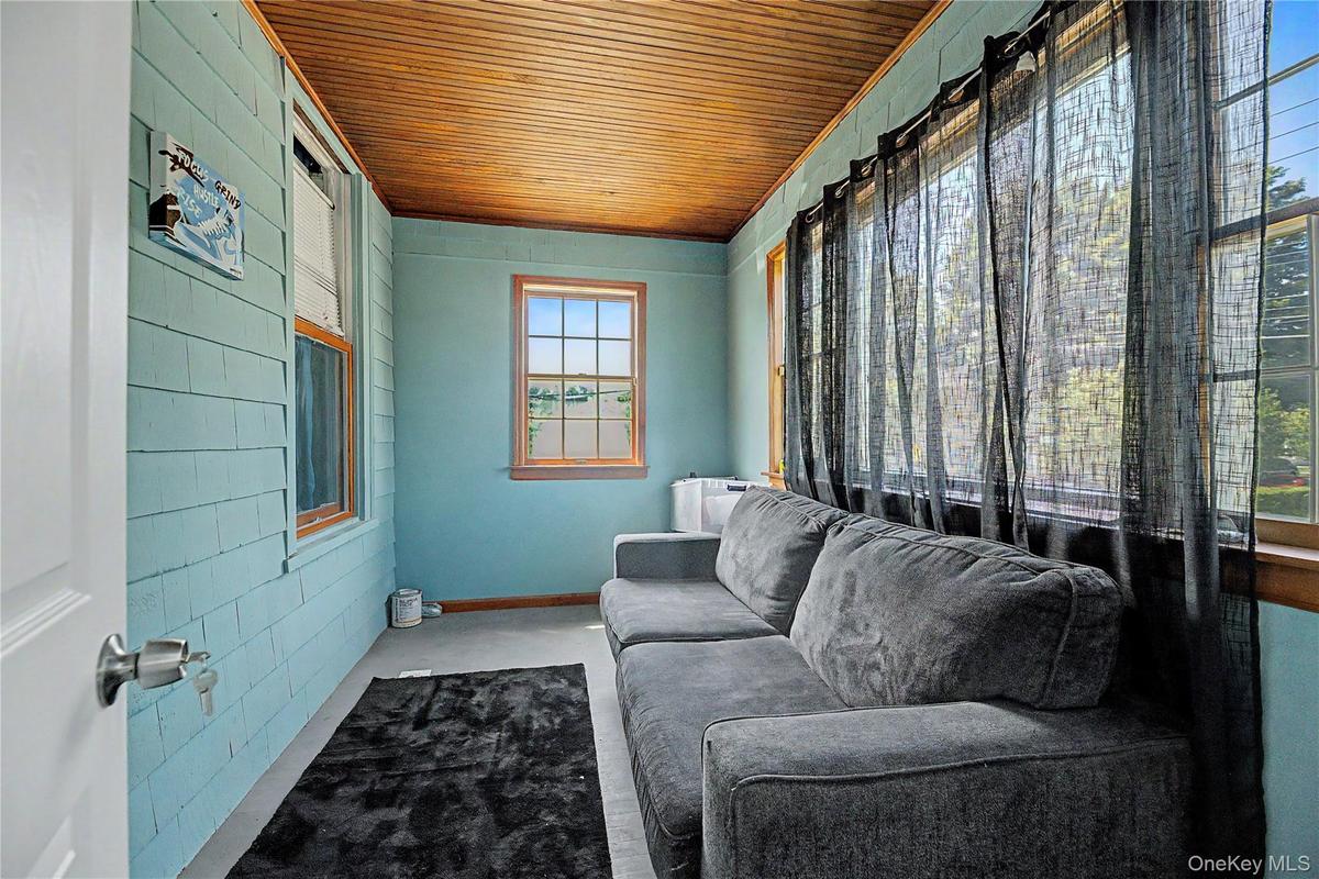 Sloped ceiling room featuring wood-finish flooring, a double window, and a flush-mount light fixture