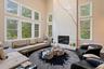 Living area with a towering ceiling, plenty of natural light, a fireplace, and wood finished floors