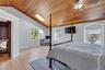 Bedroom with vaulted ceiling, wooden ceiling, multiple windows, light wood-type flooring, and an office area