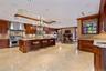 Gourmet kitchen with expansive island, recessed lighting, integrated stainless steel range with hood, custom wood cabinetry, and stone flooring