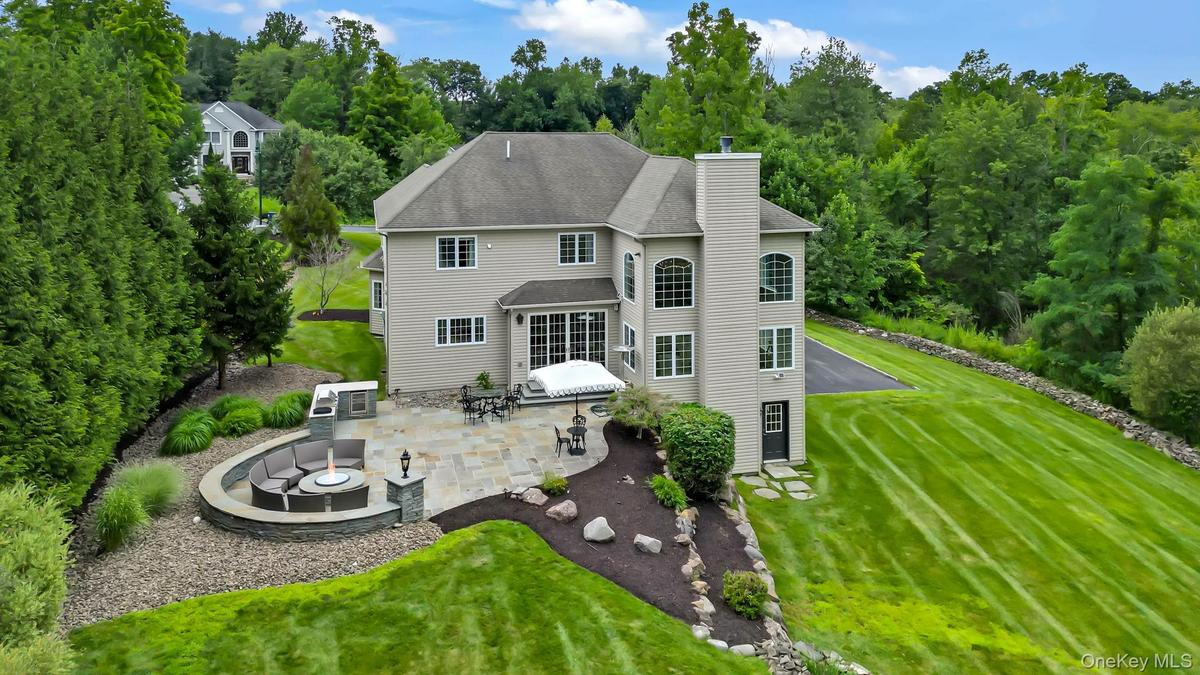 Expansive stone patio with built-in seating area and fire pit and extensive backyard.