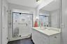 Primary bathroom with walk-in shower, vanity, dark tile patterned floors, and 2 closets.