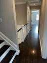 Corridor with dark wood-style flooring, ornamental molding, recessed lighting, and an upstairs landing