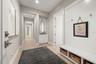 The garage entry way has built-in cabinetry and bench with hooks and storage bins.