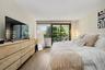 The spacious, sun-filled primary bedroom offers a serene private retreat, complete with glass doors opening to its own private balcony.