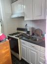 Kitchen with white cabinets, white gas stove, under cabinet range hood, and decorative backsplash