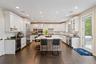 Kitchen featuring a kitchen breakfast bar, decorative backsplash, white cabinets, dark wood finished floors, and recessed lighting