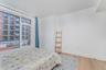Bedroom with light wood finished floors and a wall of windows