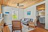 Living area with wood-finish flooring, a wood-paneled ceiling, and a ceiling fan