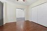 Room featuring rich wood-finish flooring, white paneled walls, and a ceiling fan