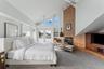 Carpeted bedroom with ceiling fan, a tile fireplace, and high vaulted ceiling