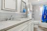 Bathroom with double vanity, shower / bathtub combination with curtain, and wood finish floors