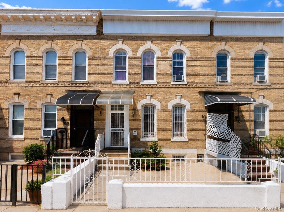 Brick exterior with arched window frames, ornate cornices, and wrought iron fencing