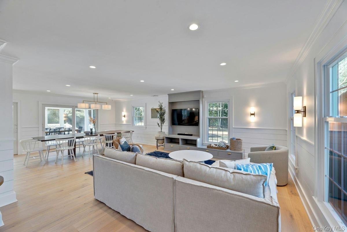 Living area with plenty of natural light, wainscoting, light wood-style flooring, crown molding, and recessed lighting