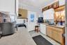 Kitchen with light countertops, black range with gas stovetop, stainless steel microwave, white cabinetry, and light brown cabinetry