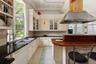 Kitchen featuring exhaust hood, tasteful backsplash, light tile patterned floors, dishwasher, and glass insert cabinets