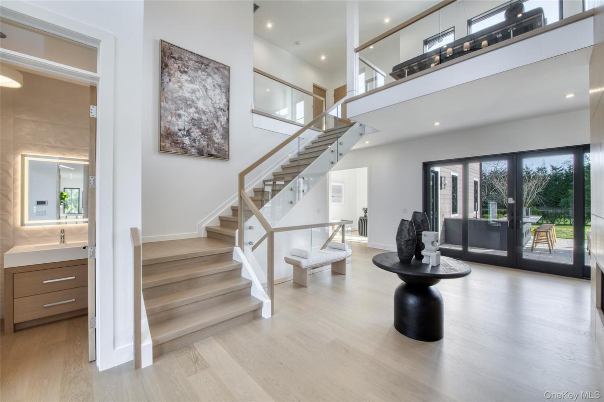 Stairs with french doors, wood finished floors, and a high ceiling
