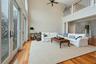 Living room with ornate columns, ceiling fan, a towering ceiling, and light wood-type flooring