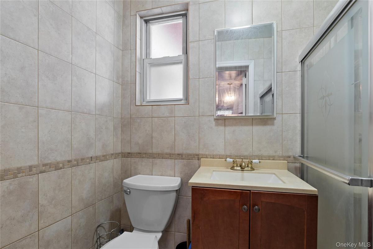 Bathroom featuring vanity, a shower stall, and tile walls