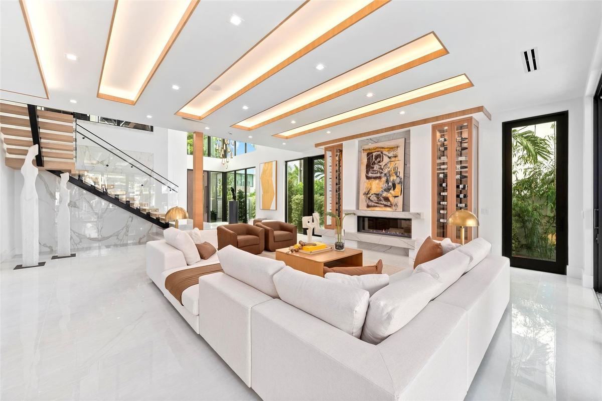 Grand open living space with soaring ceilings, breathtaking water views, a statement fireplace, and custom wine storage.