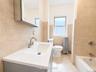 2nd fl Vanity with integrated sink, modern brushed nickel faucet, wall-mounted mirrored medicine cabinet, bathtub with shower fixture, and tiled walls