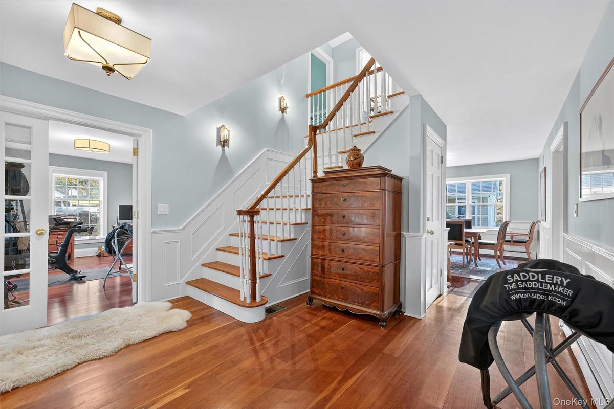 Stairway featuring wainscoting, a decorative wall, and wood-type flooring