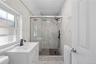 white vanity with integrated rectangular sink and matte black faucet, glass-enclosed shower, matte black shower fixtures, and white marble-look wall t