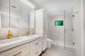 Primary ensuite bathroom with custom cabinetry, dual sinks, high end fixtures and toilet and beautifully tiled shower