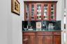 Indoor wet bar featuring dark stone counters, glass insert cabinets, and decorative backsplash