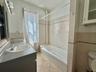 Bathroom with tile patterned flooring, shower / bathtub combination, tile walls, and vanity