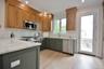 Kitchen featuring light stone countertops, backsplash, stainless steel appliances, crown molding, and light wood-style flooring