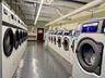 Community laundry room featuring multiple front-loading washing machines, durable flooring, and overhead fluorescent lighting