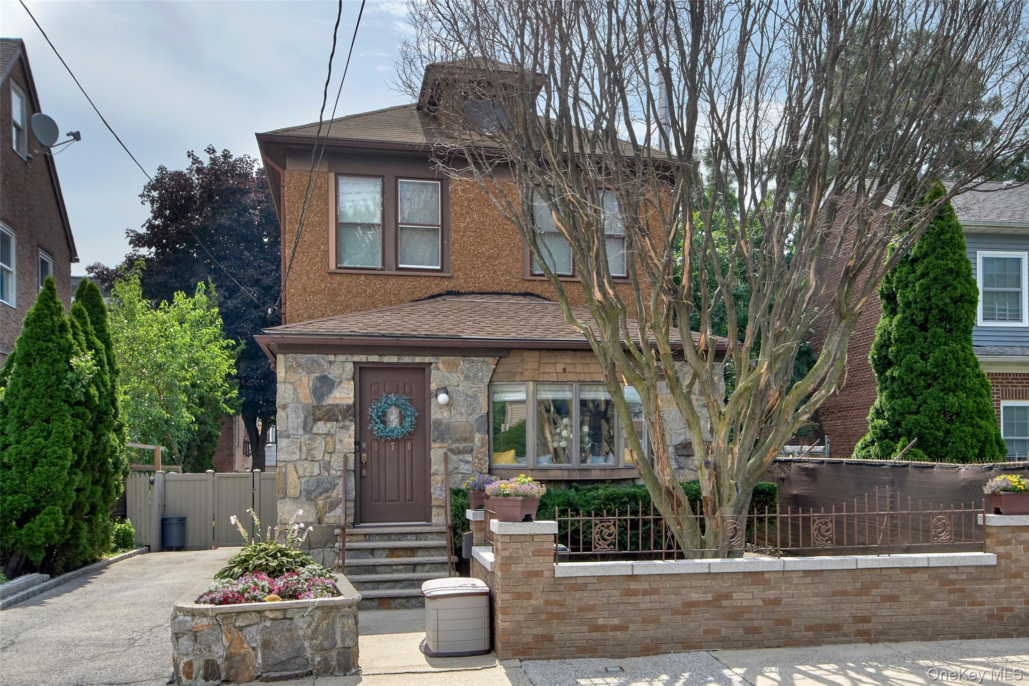 Stucco and stone facade home featuring a prominent bay window