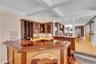 Indoor wet bar with tasteful backsplash, brown cabinets, coffered ceiling, beamed ceiling, and stainless steel fridge