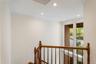 Stairwell featuring a wood-finish banister, crown molding, recessed lighting, and a large window with white trim