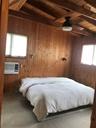 Carpeted bedroom featuring wood walls, beamed ceiling, wooden ceiling, and cooling unit