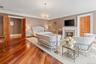Spacious room featuring rich wood-finish flooring, a decorative chandelier, and a fireplace with a white mantel