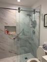 Full bathroom with a marble finish shower and toilet